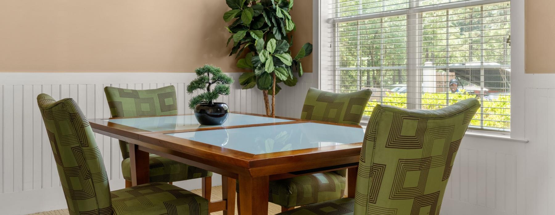 a table with chairs and plants in a room with windows